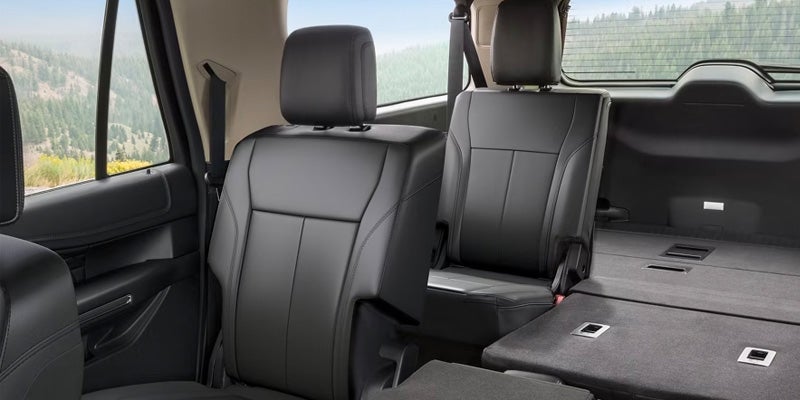 Interior of an SUV showing black leather second-row seats and the third-row seats folded flat.