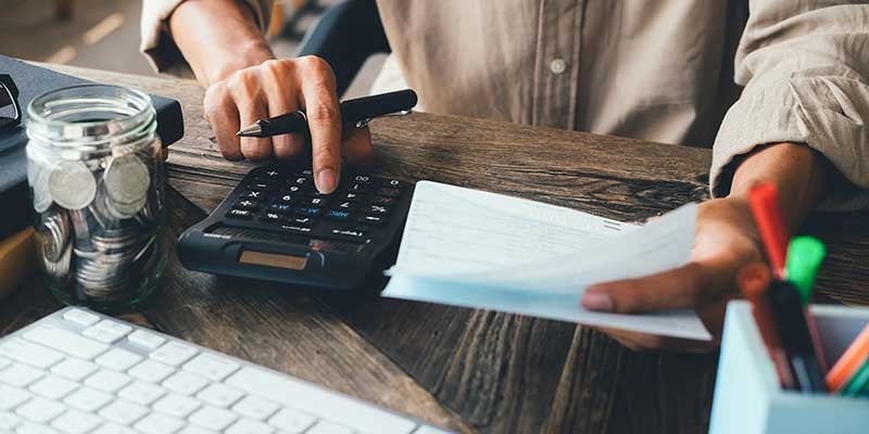A person uses a calculator and holds financial documents